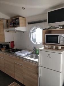 a kitchen with a white refrigerator and a microwave at Mobile-Home 6 personnes Cap Ferret in Claouey