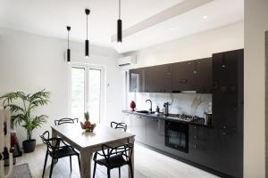 a kitchen with black cabinets and a table with chairs at CDO Apartment in Capo dʼOrlando