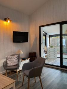 - un salon avec deux chaises et une télévision murale dans l'établissement Location maison de vacances à Sainte-Marie-Plage, à Sainte-Marie-la-Mer