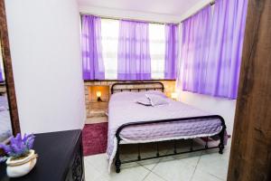 a small bedroom with purple curtains and a bed at Glicinia in Šibenik