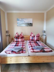 a bedroom with two beds with plaid pillows at Zum Kranichblick FeWo 1&2 in Niepars