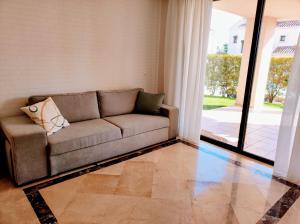 a couch in a living room with a large window at LUXURY GROUND FLOOR RODA GOLF & BEACH RESORT APARTMENT in Roda