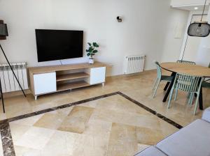 a living room with a television and a table at LUXURY GROUND FLOOR RODA GOLF & BEACH RESORT APARTMENT in Roda