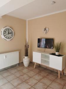 een woonkamer met een tv en een klok aan de muur bij Zum Kranichblick FeWo 1&2 in Niepars