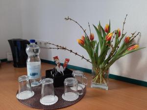 una mesa con una botella y vasos y un jarrón con flores en Hotel & Restaurant Eichholz en Kassel