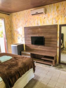 a bedroom with a bed and a flat screen tv at Pousada Sol Da Pipa in Pipa
