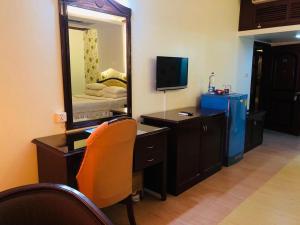 Schlafzimmer mit einem Schreibtisch, einem Spiegel und einem Bett in der Unterkunft Grand Park Hotel in Chittagong