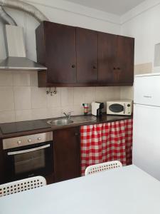 een keuken met houten kasten, een wastafel en een fornuis bij Casa Gil Vicente in Évora