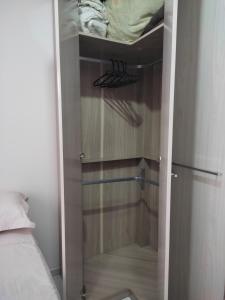 a closet with a glass door with a bed at Um quarto em casa agradável in Perequê