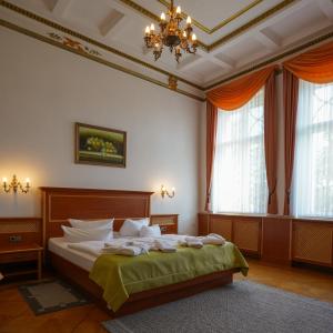 a bedroom with a bed and a chandelier and windows at Hotel Seeschlösschen in Groß Köris