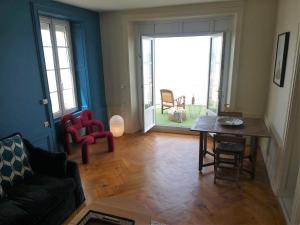 uma sala de estar com um sofá, uma mesa e cadeiras em Appartement de standing - avec terrasse et vue mer em Arromanches-les-Bains