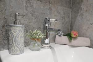 a bathroom sink with a faucet and flowers on it at Apartament Południowy in Ruda Śląska