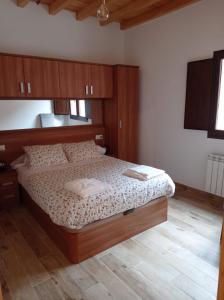 - une chambre avec un lit et une tête de lit en bois dans l'établissement Casa Rural Güilones, Parque Natural de Ponga, à Sobrefoz