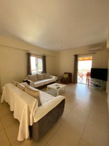 ein Wohnzimmer mit zwei Sofas und einem Fernseher in der Unterkunft Gkiko’s Guest House in Qeparo