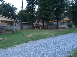 a yard with a playground and trees and a house at Anglers Hideaway Cabins in Mead