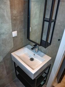 W łazience znajduje się biała umywalka i lustro. w obiekcie Luxury Suites VASKO 1 w Salonikach