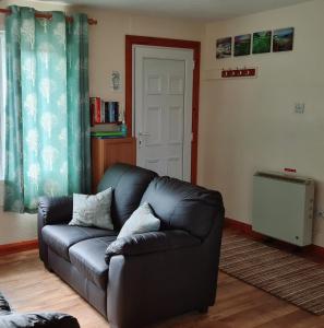 - un canapé en cuir noir dans le salon avec une porte dans l'établissement Detached Bungalow in North Cornwall, à Bodmin