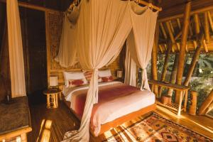 a bedroom with a canopy bed in a room at Ananda House 3bds Eco Bamboo House Pool River View in Bringkit