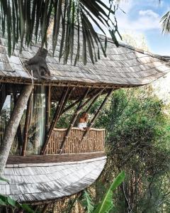 une femme assise dans un hamac avec un singe dessus dans l'établissement Ananda House 3bds Eco Bamboo House Pool River View, à Bringkit