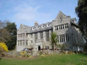an old stone mansion with a palm tree in front of it at Detached Bungalow in North Cornwall in Bodmin