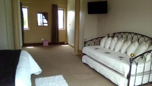 a bedroom with two beds with white sheets and a television at Uyolo Guest Logde in Port Elizabeth