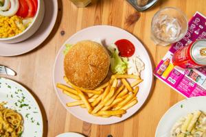 a plate of food with a hamburger and french fries at Safestay Pisa Centrale in Pisa