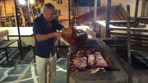 a man standing next to a grill with meat at Gran Aldea Hotel in Capilla del Monte