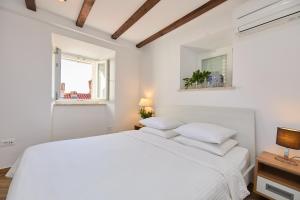 Un dormitorio blanco con una cama blanca y una ventana en Heritage Vista, en Dubrovnik