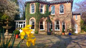 a brick building with yellow flowers in front of it at Ravenscroft B&B in Mansfield