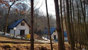 uma casa branca com um telhado azul na floresta em Domki Łowisko Wieniec em Gdów