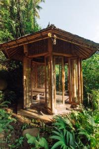 een kleine houten structuur midden in een bos bij Temple House 3bds Eco Bamboo House Pool River View in Bringkit