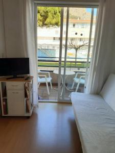 a bedroom with a bed and a television and a balcony at Apartaments Blau Park in L'Estartit