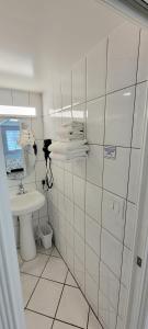 a white tiled bathroom with a sink and a mirror at Satellite Motel in St Pete Beach