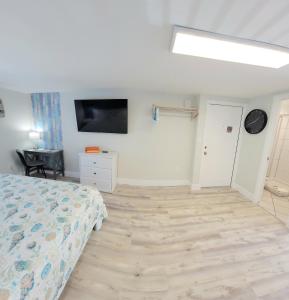 um quarto com uma cama e uma televisão de ecrã plano em Satellite Motel em St. Pete Beach