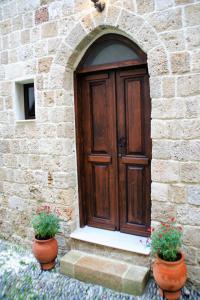 a wooden door in a stone building with two potted plants at Evangelia's Little House in Rhodes Town