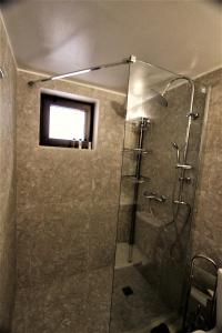 bagno con doccia e porta in vetro di Evangelia's Little House a Città di Rodi