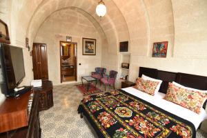 a bedroom with a bed and a television in a room at Canela Cave Hotel - Cappadocia in Göreme