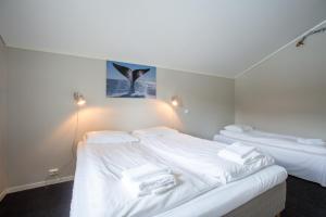 two beds in a room with white sheets and towels at Sauda Fjord Camping in Saudasjøen