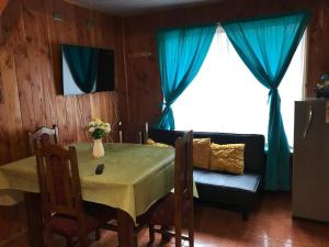 a dining room with a table and a couch at Cabañas Costanera in Villarrica