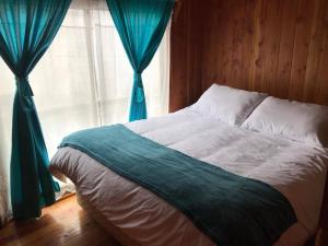 a bedroom with a bed with blue curtains and a window at Cabañas Costanera in Villarrica