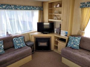 sala de estar con 2 sillas, TV y chimenea en 341 Family Caravan at Marine Holiday Park, sleeps 6, en Rhyl