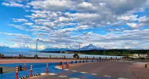 a road next to a body of water with mountains at Cabañas Costanera in Villarrica