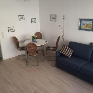 sala de estar con sofá, mesa y sillas en Ferienwohnung-Winora, en Westerland