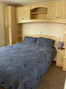 a bed with a blue comforter in a room at 341 Family Caravan at Marine Holiday Park, sleeps 6 in Rhyl