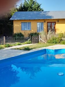 a house with a blue swimming pool in front of a house at Complejo Dulcería El Cazador y cabañas in Tandil