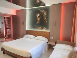 Hotel Camelia في كاميري: سريرين في غرفة مع لوحة على الحائط