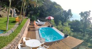 a swimming pool with a table and chairs and an umbrella at Suite com piscina in Florianópolis