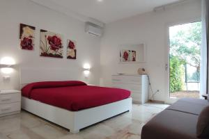 a white bedroom with a red bed and a window at Villetta Lu Sciardinu in Otranto