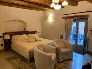 Cedegolo的住宿－Foresteria Antica Farmacia，一间卧室配有一张床、两把椅子和一个窗户