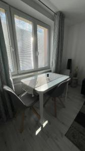 stół i krzesło w pokoju z oknami w obiekcie Apartment Hospodárska w mieście Trnava